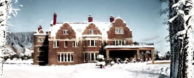 Snow-covered Erlowest castle in Lake George surrounded by winter trees and landscape